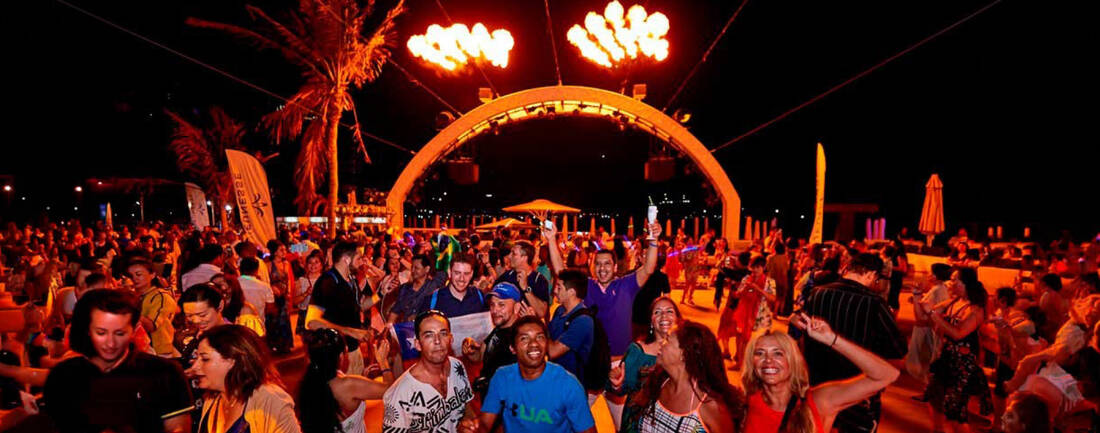 People at a night event looking at the camera with fire in the background
