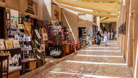 Two women walk past a colourful stall in the Al Fahidi souk