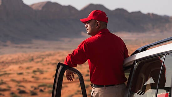 A dnata representative standing outside his vehicle in the desert