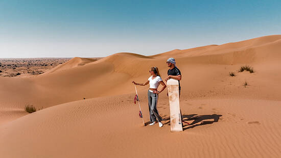 A couple looking out into the desert with sandboards