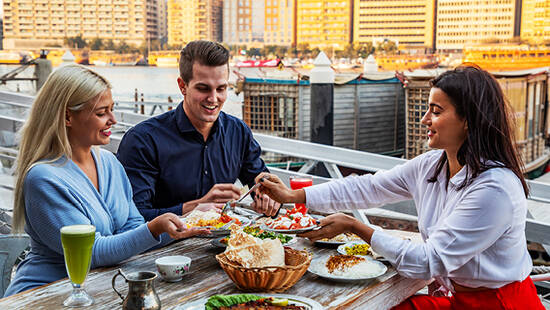 Three people sharing food at a restaurant at the Al Fanar restaurant in Dubai