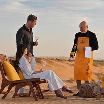 a Veuve Clicquot Desert chef serving wine to a couple