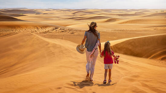 A mother and daughter walking across the desert