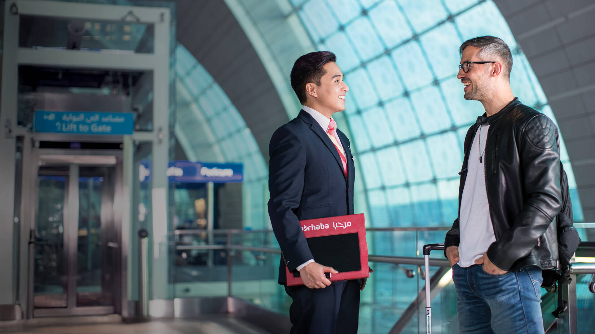 A marhaba team member standing with a passenger and smiling