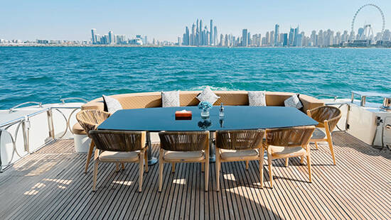 A dining table on the deck of a yacht overlooking the Dubai Skyline