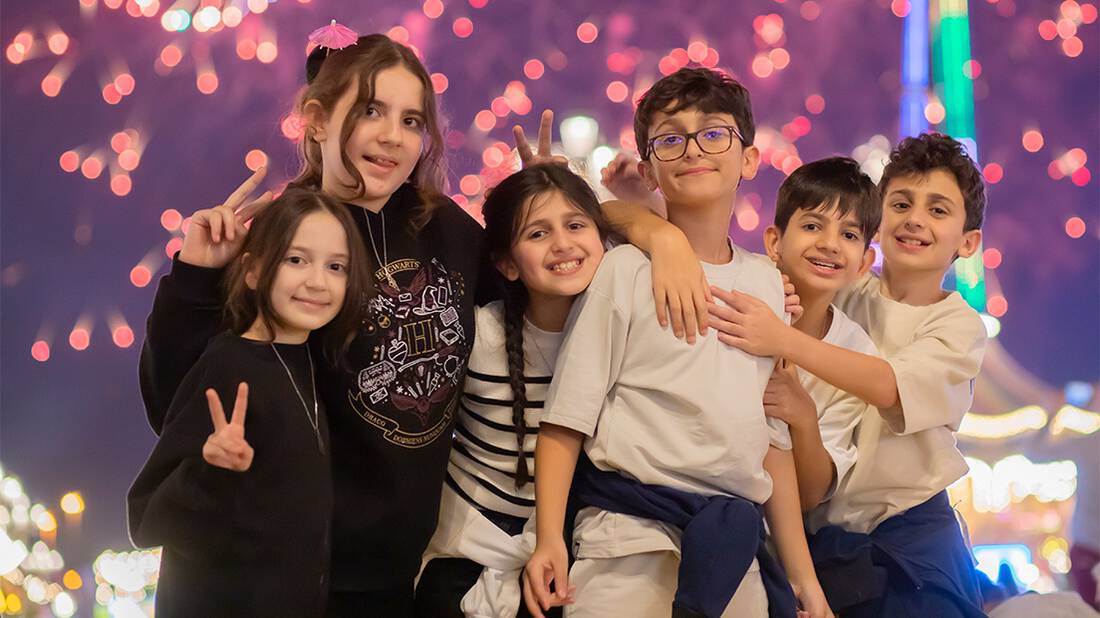 A group of kids gathered for a photo against the fireworks display 
