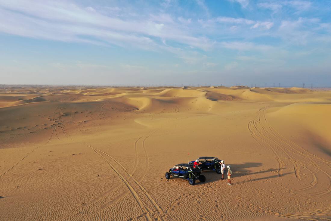 A couple of dune buggy drivers standing next to their dune buggies in the desert