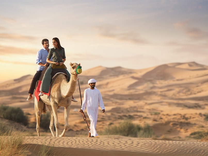 A couple riding a camel through the desert