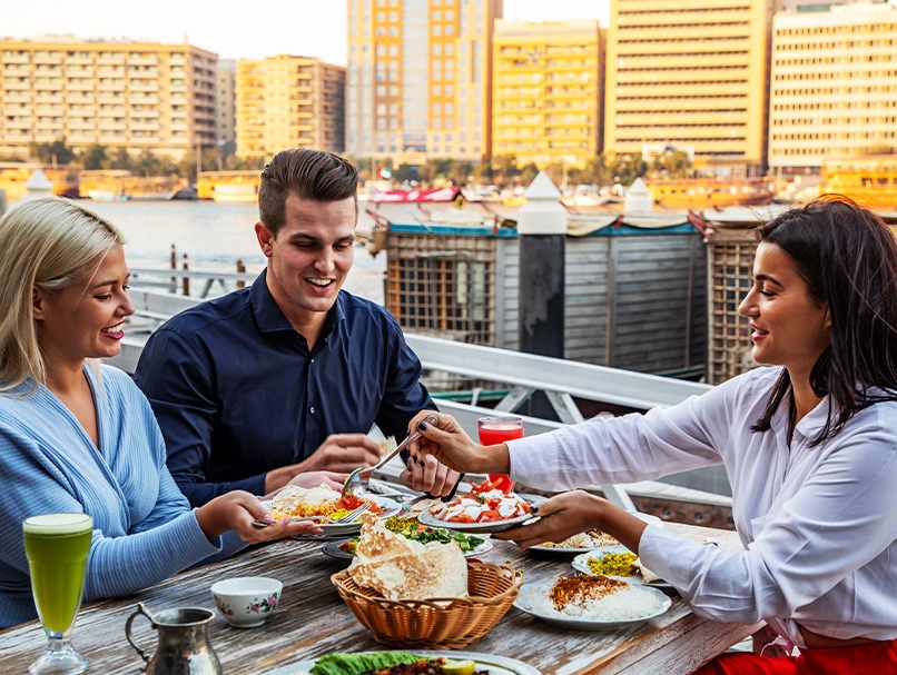 A group sharing food at a waterfront restaurant in Dubai
