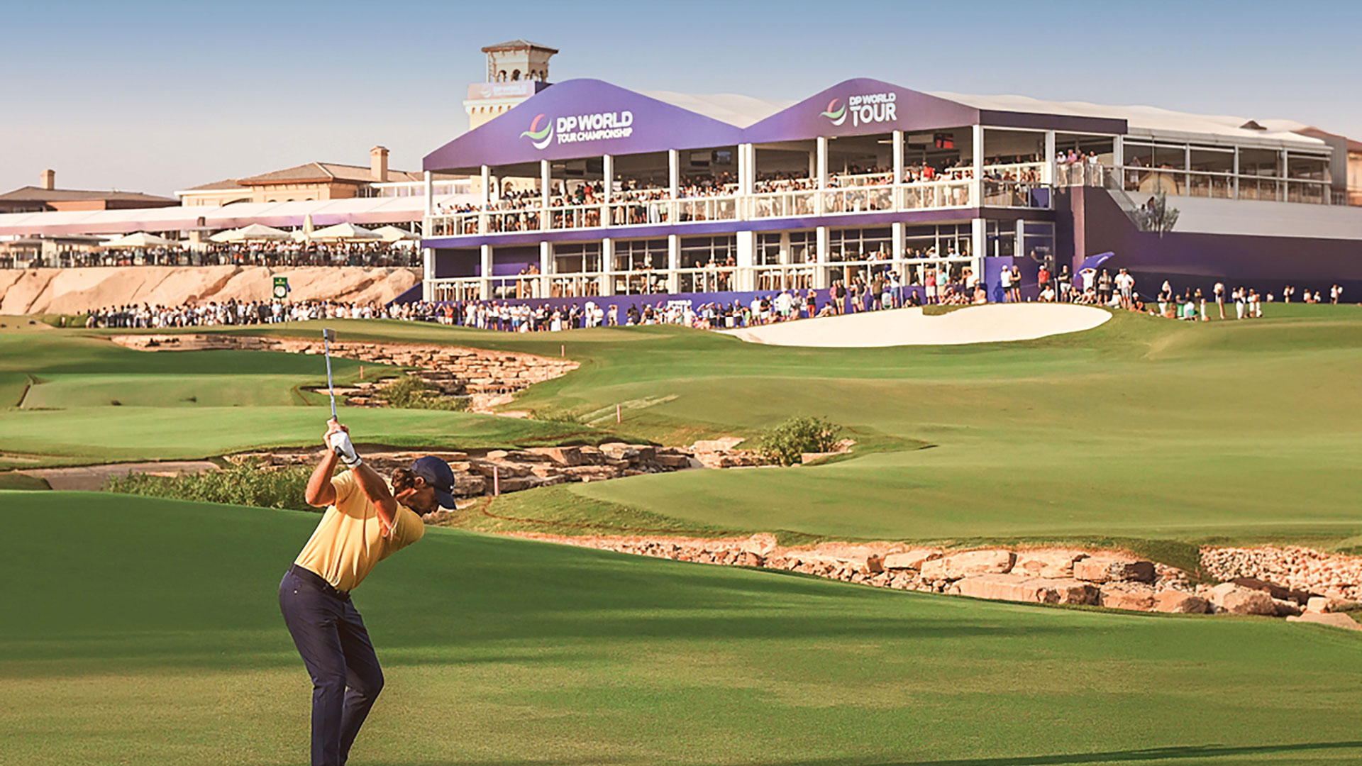 A golfer ready to hit a golf ball by a DP World Tour building on the golf course