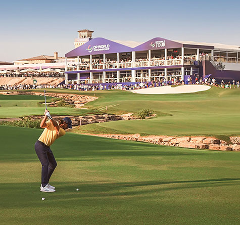 A golfer ready to hit a golf ball by a DP World Tour building on the golf course