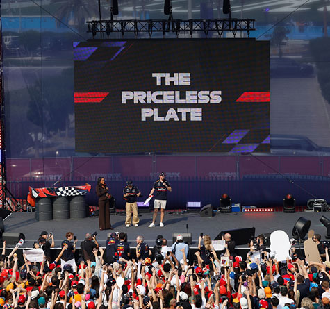 Fans in front of a staging with 3 hosts and text displayed about The Priceless Plate