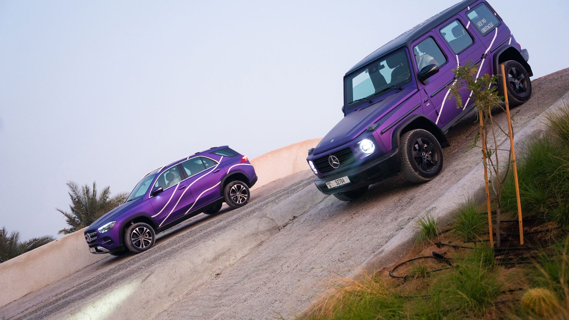 A purple Mercedes Benz GLE and a G Class going down a slope on a city off-roading course
