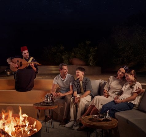 A family seated in sunken fire pit with oud player playing the oud