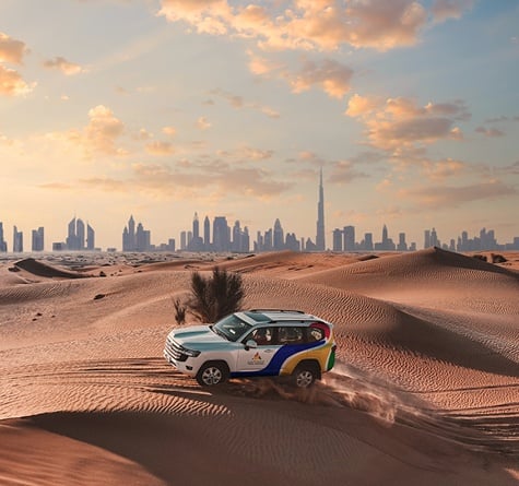 An Arabian Adventures Jeep in the desert at sunset against the Dubai skyline