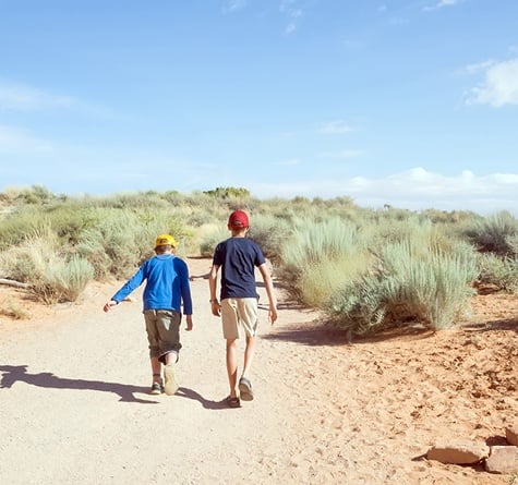 Two children waking ahead on an exploration hike in the desert