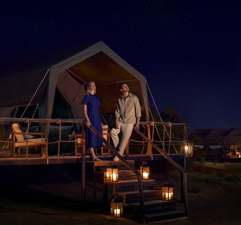 A couple standing at the porch of the glamping overnight cabana