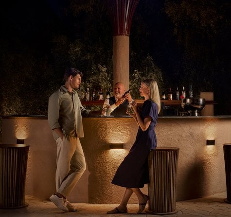 A couple standing at a bar with a bartender preparing drinks for them