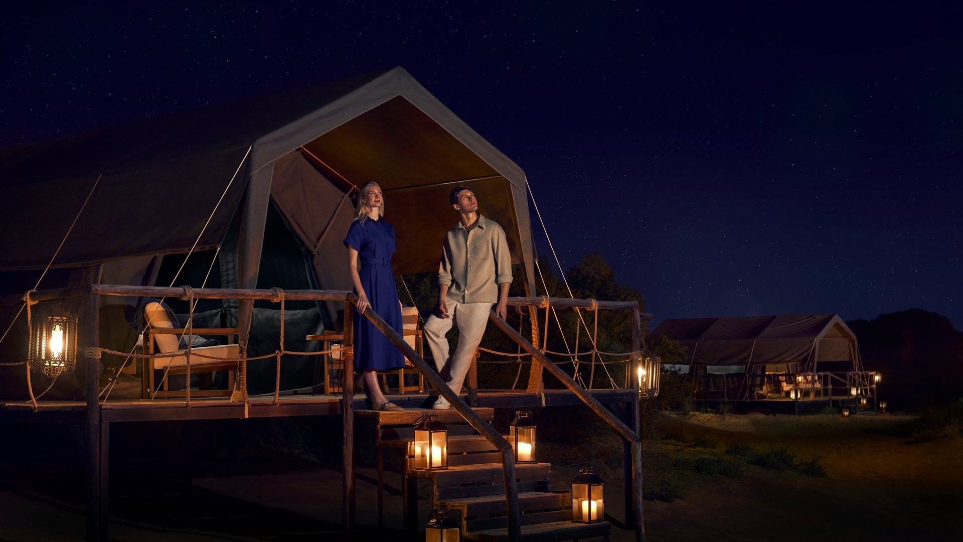 A couple standing at the porch of the glamping overnight cabana
