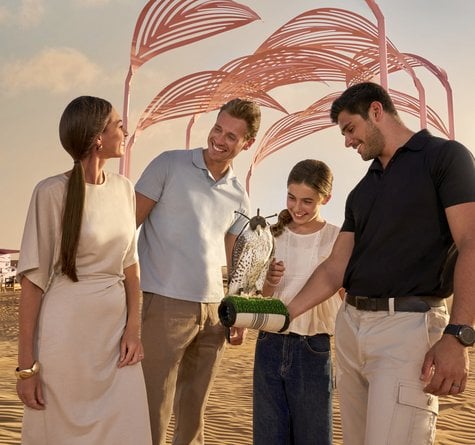 Couples in fancy attire at Nomad Garden entrance looking at an eagle one of the men is holding