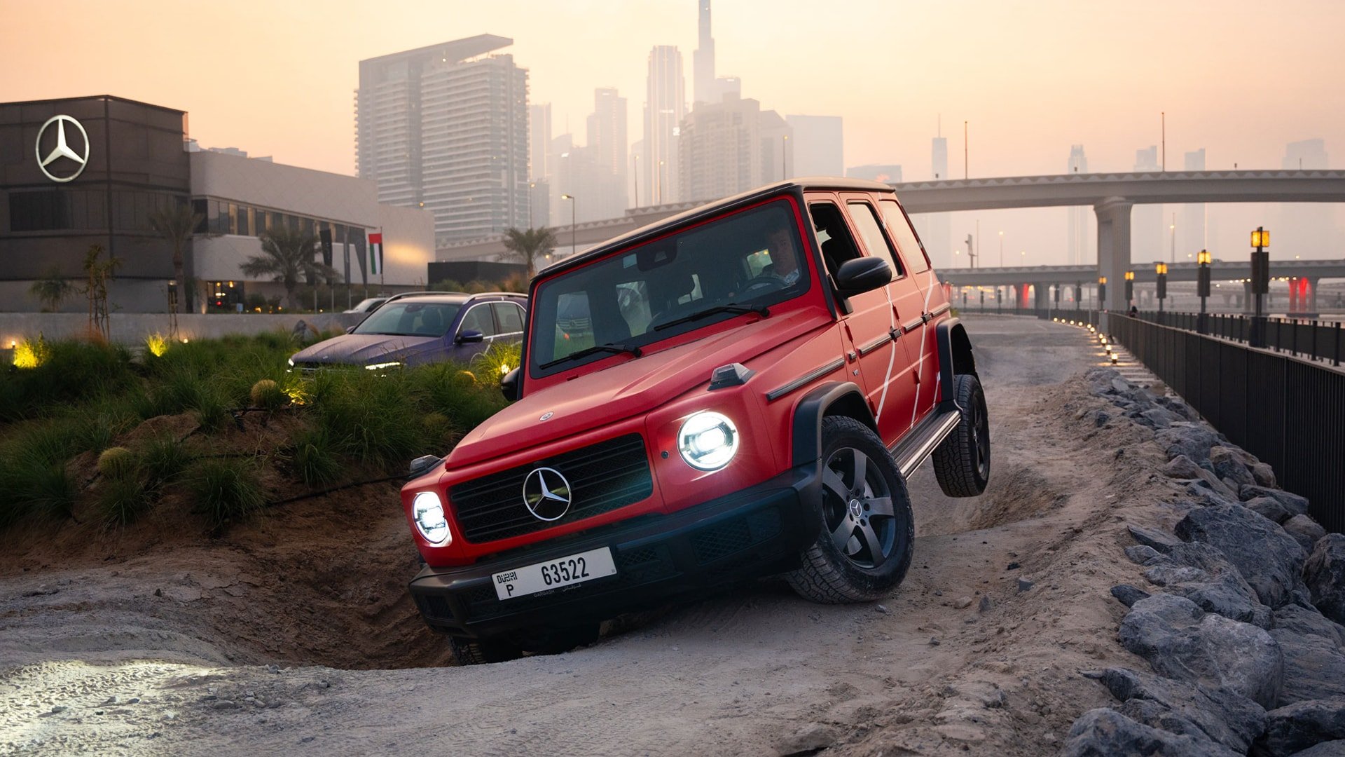 A red Mercedes Benz G-Class on an off-road course at sunset